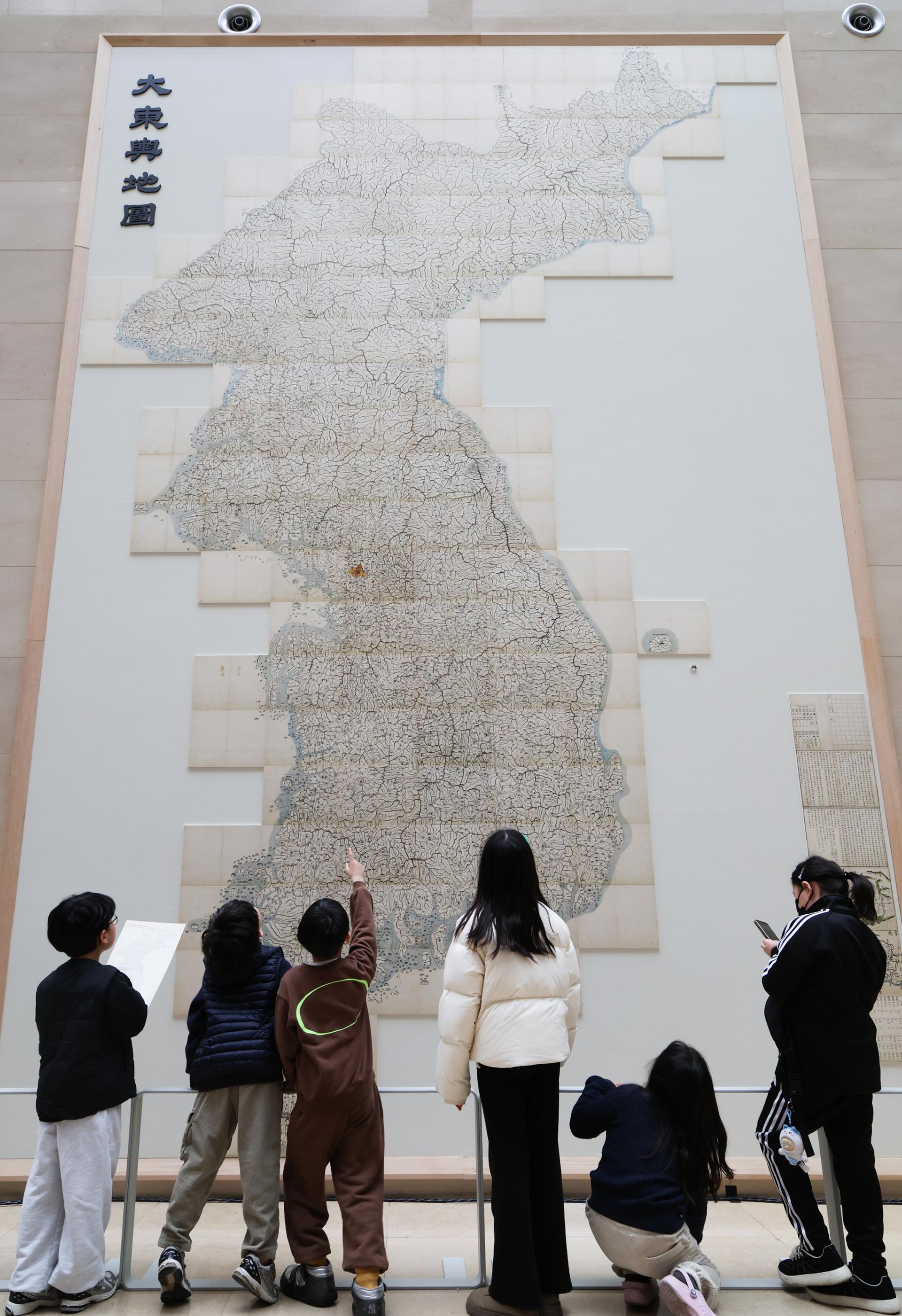 Jóvenes visitantes observan "Daedongyeojido", un mapa emblemático de la península de Corea del siglo XIX, realizado por el cartógrafo Kim Jeong-ho, expuesto en el vestíbulo principal del Museo Nacional de Corea
